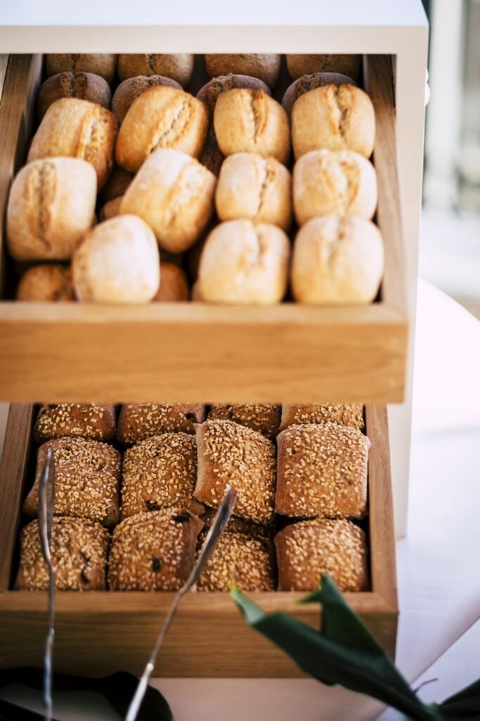 Bread buns in abundance on display at slatted shelf fixture in hotel or supermarket for sale